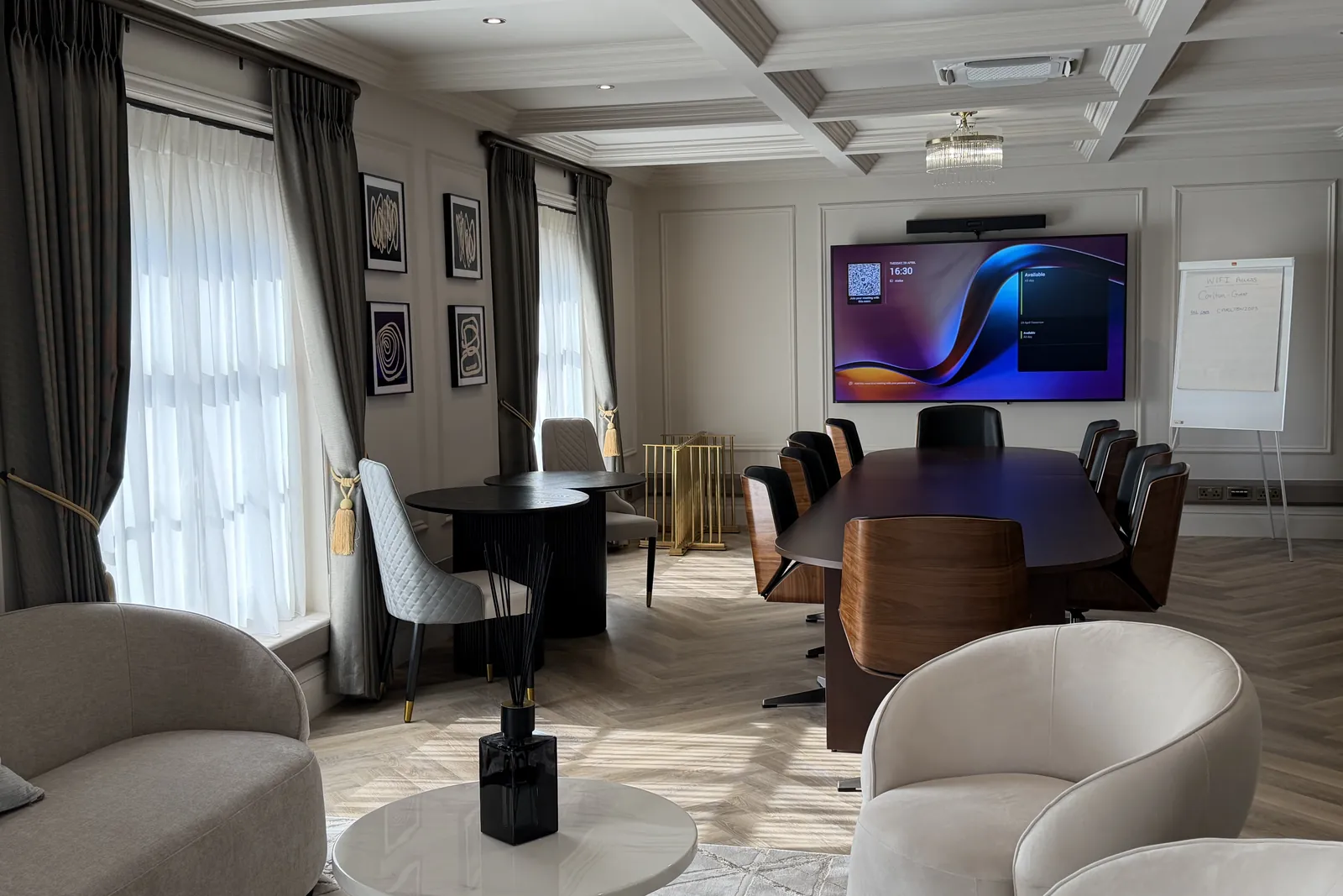 Atelier, the members’ floor: a walnut boardroom table, a screen, and a lounge of pale armchairs