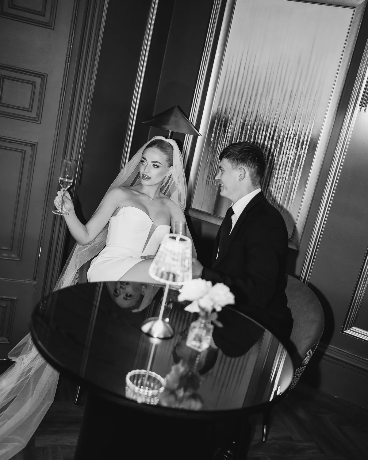A couple at a round table in Nocturne, a crystal lamp between them, the mirrored panelling behind