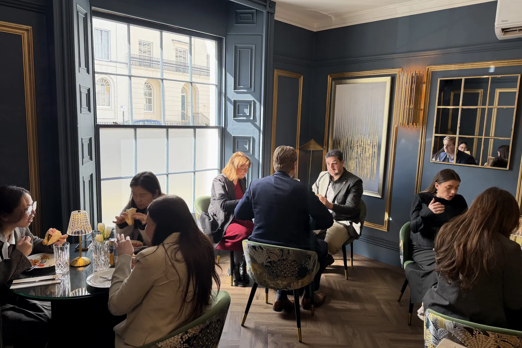 Guests at the tables in Nocturne by the tall sash window