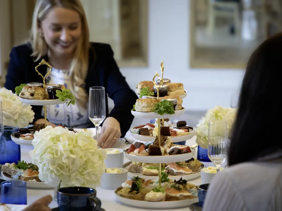 Guests at an afternoon tea with tiered stands, champagne and white hydrangeas