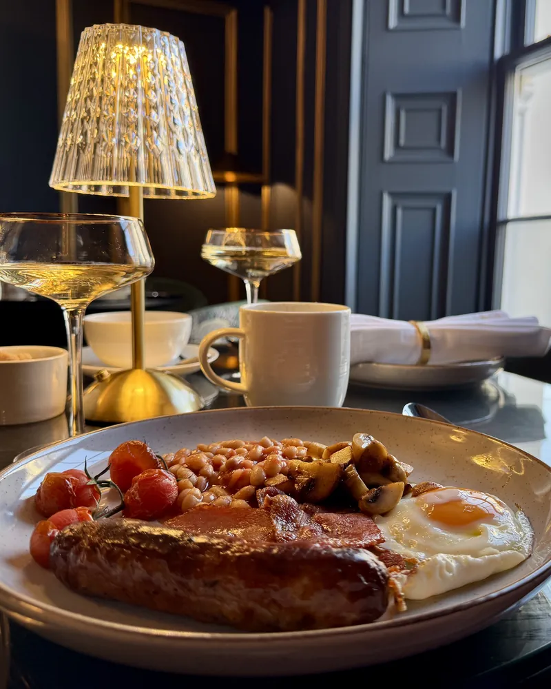 A cooked breakfast served at a lamplit table by the window in Maison D'Or