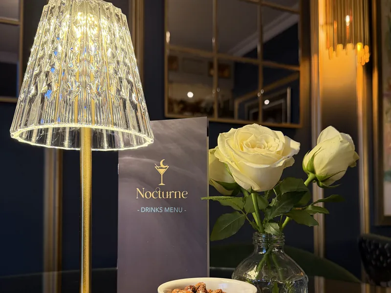 A crystal table lamp, white roses and the Nocturne drinks menu