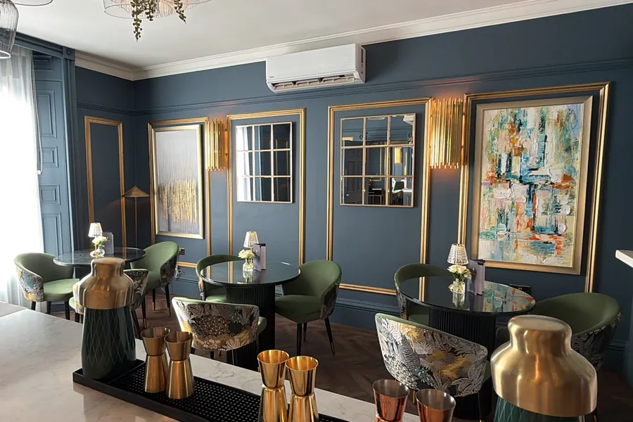 The lounge in Nocturne with green velvet chairs and abstract art
